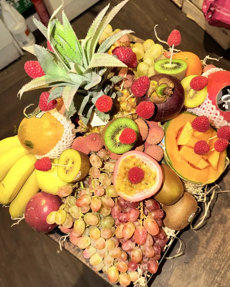 Corbeille de fruits exotiques : ananas, framboises, litchis, mangoustan, fruit de la passion, kiwis, melon, mangue, bananes et raisin