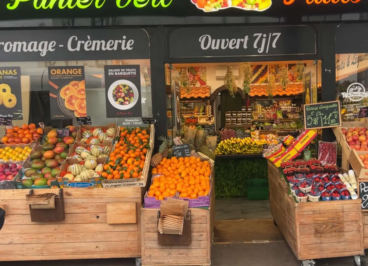 La devanture du Panier Vert : cagettes de clémentines, melons, mangues et fraises devant les vitrines « Fromage - Crèmerie » et « Ouvert 7j/7 »
