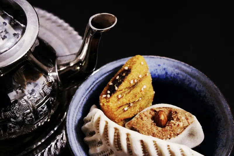 Pâtisseries orientales dans un bol, à côté d'une théière en métal