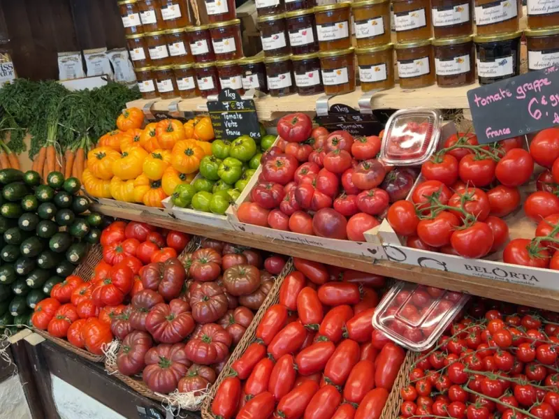 Tomates anciennes rouges, noires, jaunes et vertes, tomates grappe et cerise, courgettes et carottes, sous une étagère de confitures